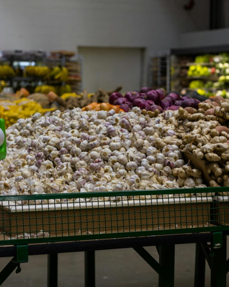 An assortment of fresh garlic and vegetables displayed at an indoor market stall.